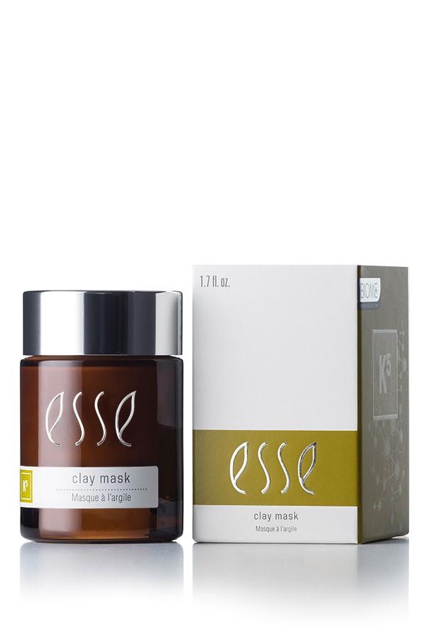A jar of Esse Clay Mask positioned beside its box. The jar features a dark brown color with a black lid and a white label displaying the product name "Esse Clay Mask." The predominantly white box has green and beige accents, along with similar branding text.