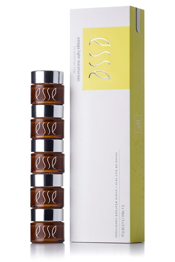 Image of a skincare product set from Esse. The set includes five small brown jars with silver lids stacked on top of one another, and a tall rectangular white and yellow box with the Esse logo and the text "Esse Omega Light Moisturizer.