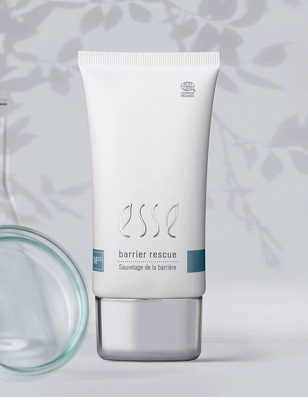 A white tube labeled “Import placeholder for 57617” stands upright on a light surface with a blurred glass container and leafy shadows in the background.